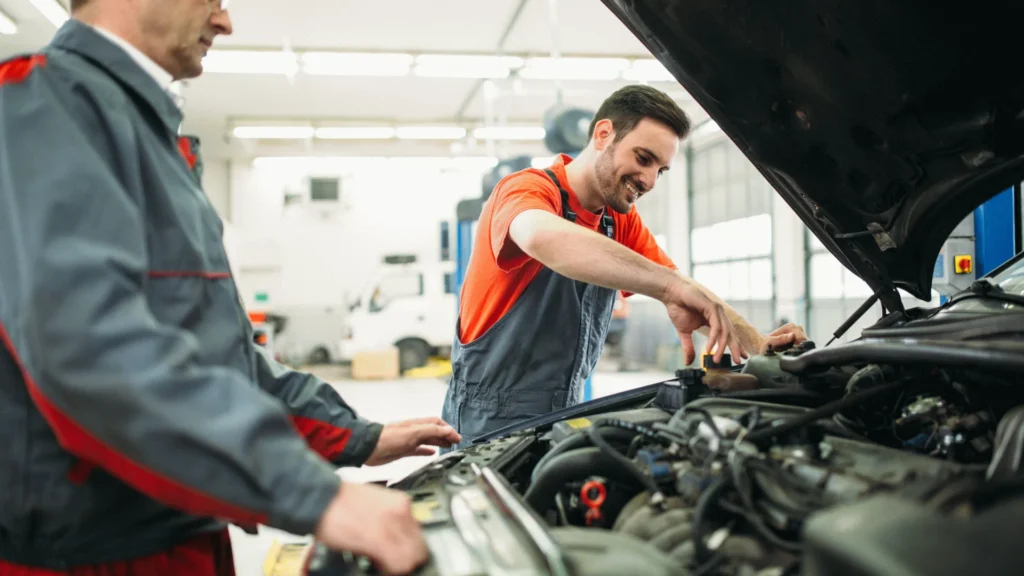 Automotive technicians performing maintenance on a vehicle engine in a service garage