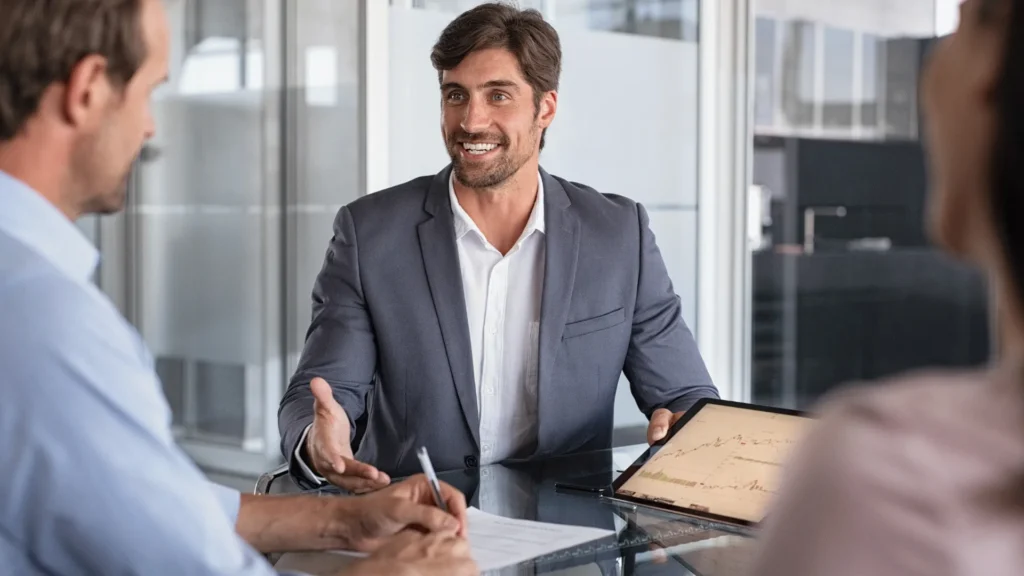 Business professionals discussing strategy during a meeting with performance data displayed on a tablet