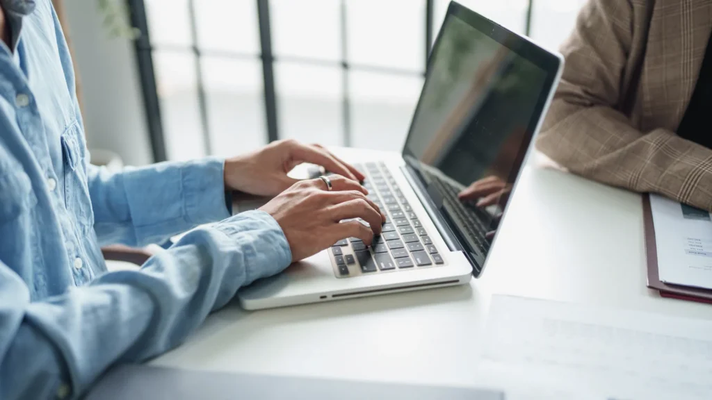 Professional typing on a laptop during a collaborative meeting